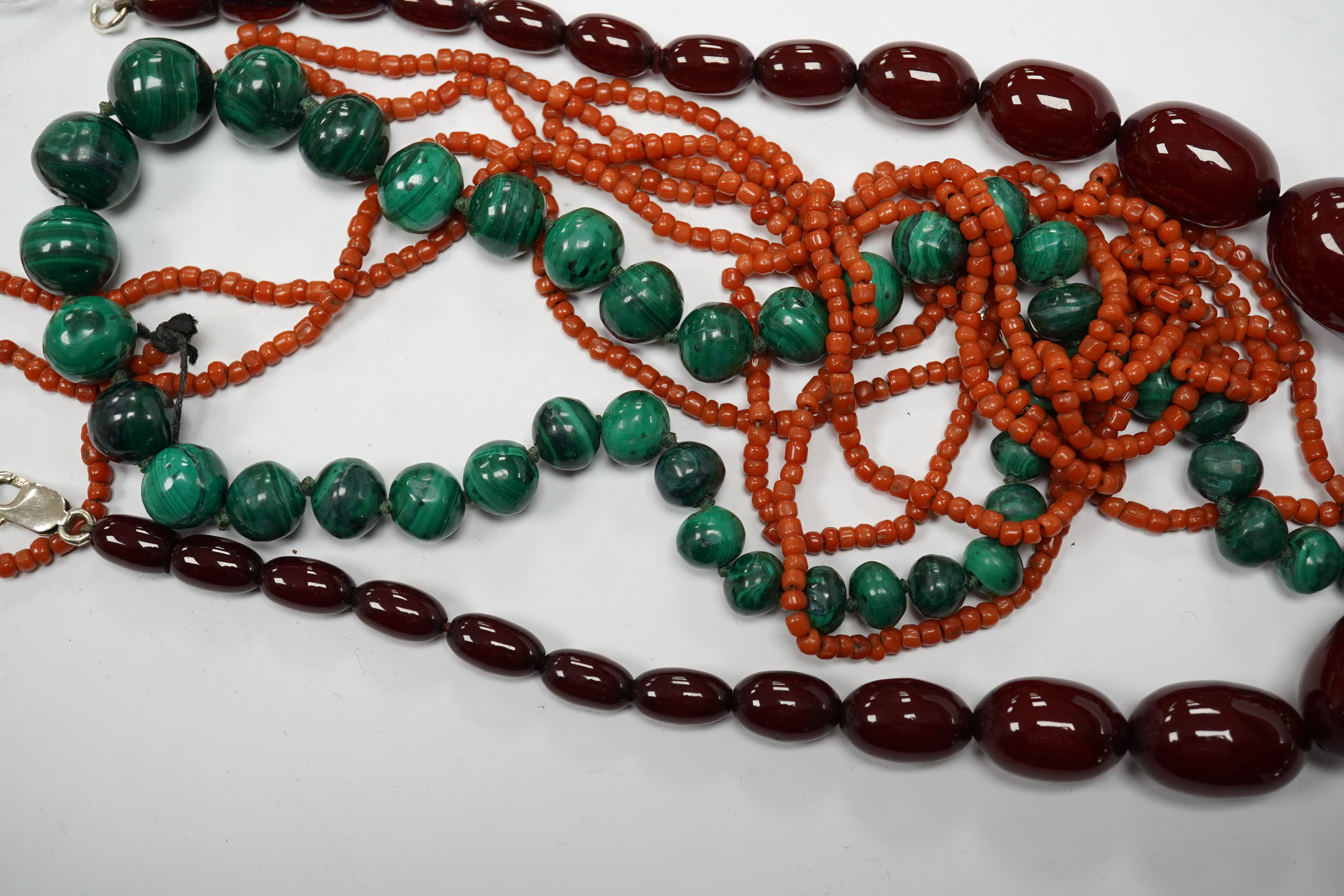 A graduated simulated cherry amber bead necklace, 43cm, gross weight 54 grams and two other necklaces including malachite. Condition - fair to good